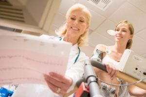 female doctor looking at chart while female patient is on a treadmill